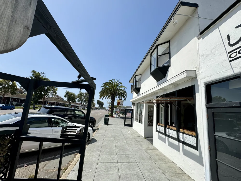 Sidewalk view of the white Encinitas Coworking building with large windows